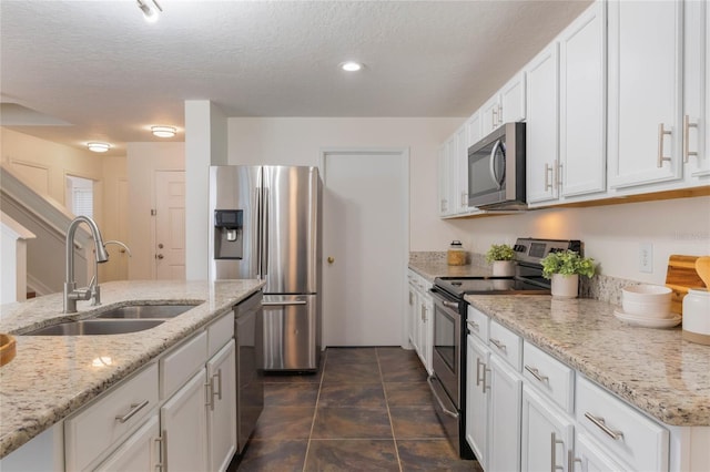 kitchen featuring light stone counters, sink, stainless steel appliances, and white cabinets