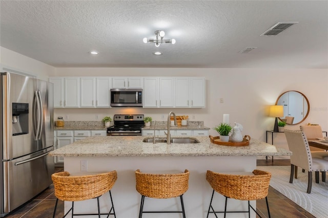 kitchen with white cabinetry, appliances with stainless steel finishes, sink, and a center island with sink