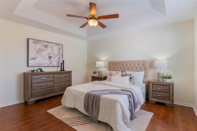 bedroom with a raised ceiling, dark hardwood / wood-style floors, and ceiling fan