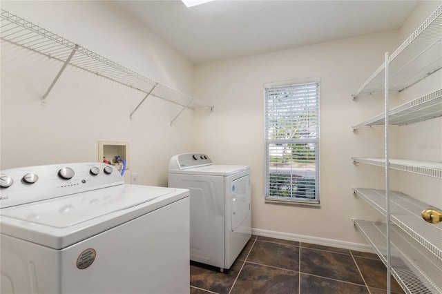 laundry room with separate washer and dryer and dark tile patterned flooring