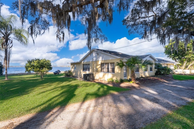 view of home's exterior with a yard, a water view, and central AC