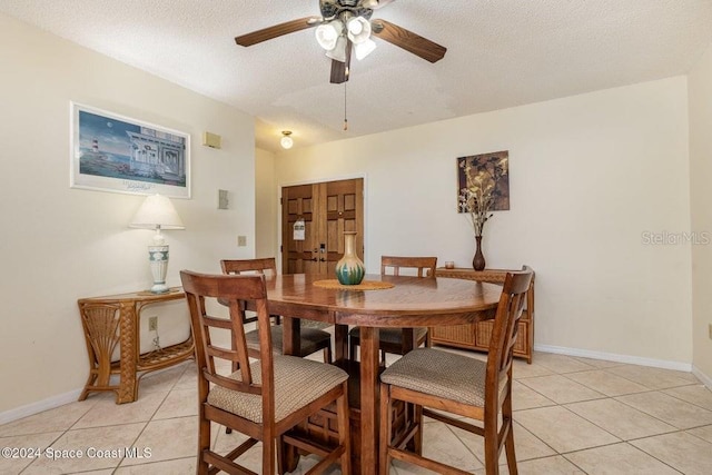 tiled dining space featuring a textured ceiling and ceiling fan