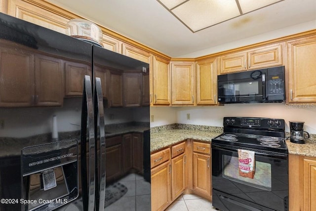 kitchen with light tile patterned floors, light stone counters, and black appliances