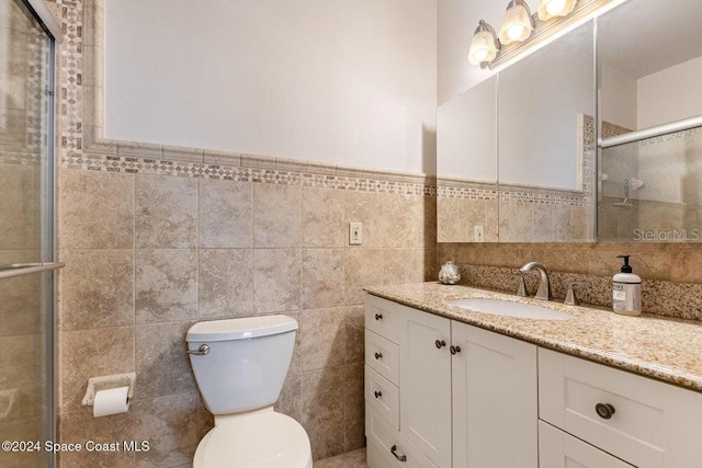 bathroom featuring an enclosed shower, vanity, toilet, and tile walls