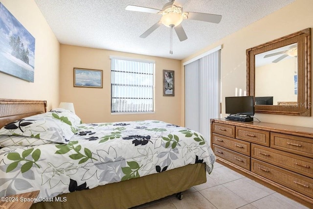 bedroom featuring ceiling fan, light tile patterned flooring, and a textured ceiling