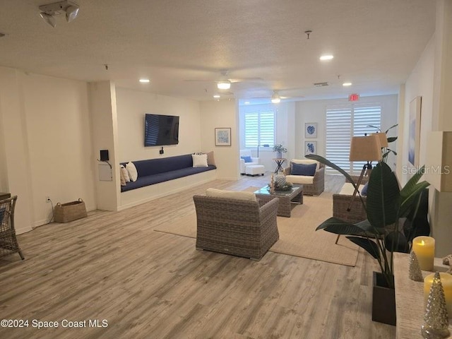 living room featuring ceiling fan, light hardwood / wood-style floors, and a textured ceiling