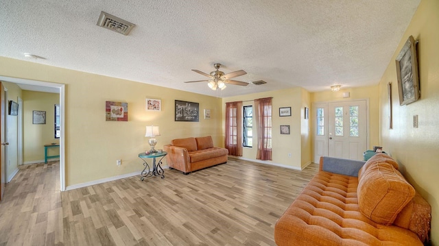 living room featuring ceiling fan, a textured ceiling, and light hardwood / wood-style flooring