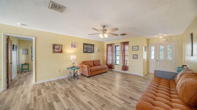 living room featuring ceiling fan, a textured ceiling, and light wood-type flooring