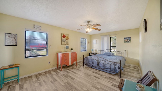 bedroom with ceiling fan, a textured ceiling, and light hardwood / wood-style floors