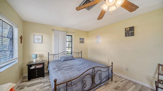 bedroom with light wood-type flooring, ceiling fan, and a textured ceiling