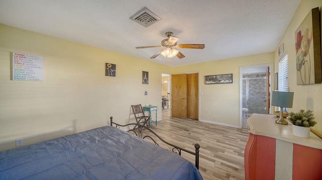 bedroom featuring ceiling fan, a textured ceiling, ensuite bath, and light wood-type flooring