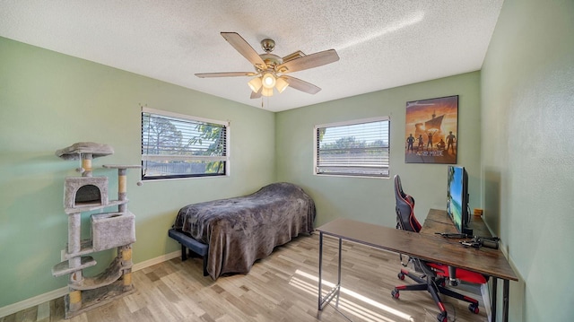 bedroom with ceiling fan, light wood-type flooring, and a textured ceiling