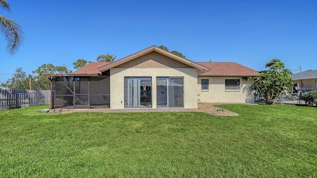 back of property with a sunroom and a lawn