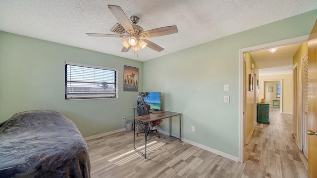 bedroom featuring a textured ceiling, ceiling fan, and light hardwood / wood-style floors