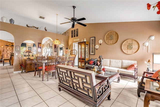 living room featuring ceiling fan with notable chandelier, light tile patterned floors, and vaulted ceiling