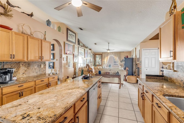 kitchen with dishwasher, ceiling fan, light stone countertops, light tile patterned floors, and tasteful backsplash