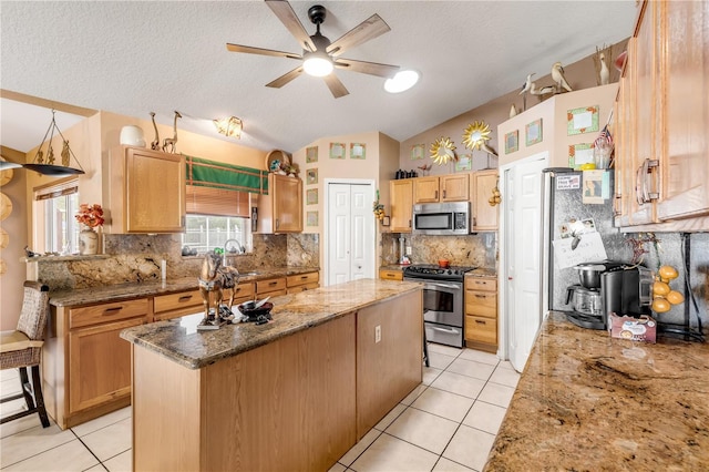 kitchen featuring stainless steel appliances, a kitchen island, backsplash, lofted ceiling, and light tile patterned floors