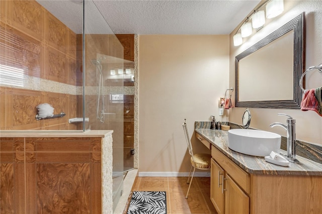 bathroom featuring tile patterned floors, vanity, a tile shower, and a textured ceiling