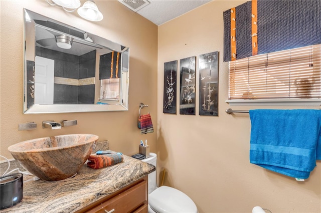 bathroom featuring a textured ceiling, vanity, and toilet