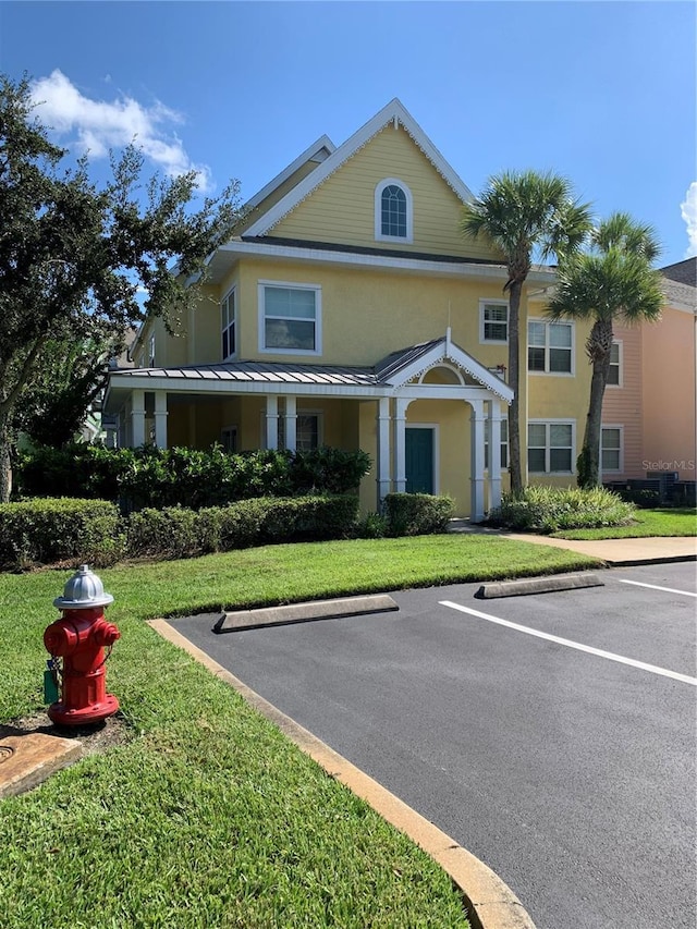 view of front of house with uncovered parking, a front lawn, and stucco siding