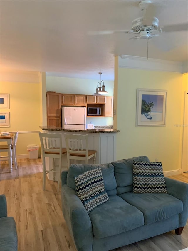 living room with ceiling fan, light wood-type flooring, and ornamental molding