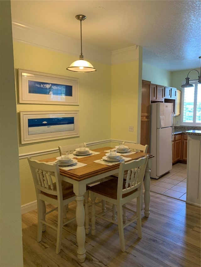 dining area with crown molding, light hardwood / wood-style floors, and a textured ceiling