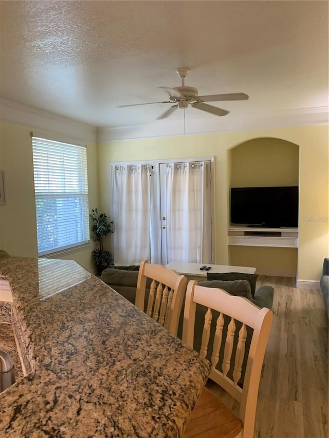 dining area featuring a textured ceiling, light hardwood / wood-style floors, ceiling fan, and ornamental molding