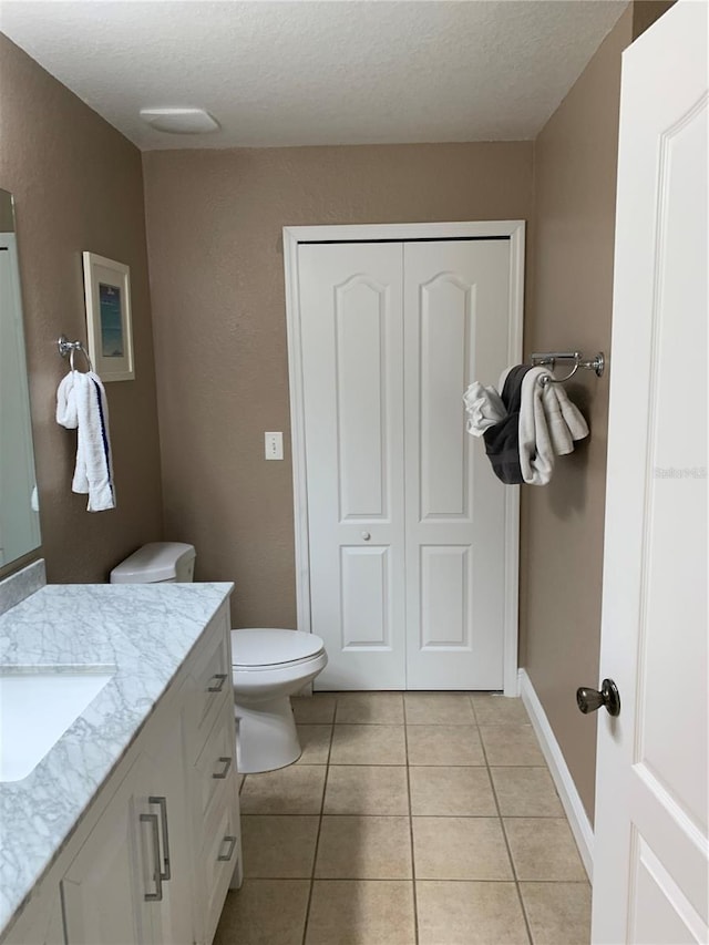 bathroom with tile patterned floors, vanity, a textured ceiling, and toilet