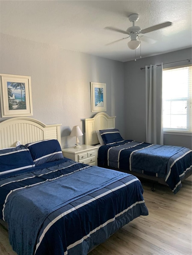 bedroom featuring ceiling fan, light wood-type flooring, and a textured ceiling