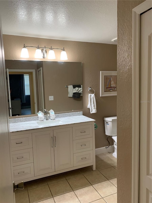 bathroom with tile patterned floors, vanity, a textured ceiling, and toilet