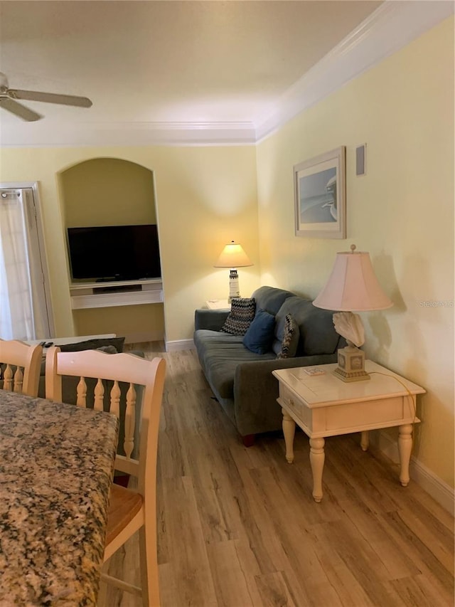 living area with light wood-type flooring, baseboards, ornamental molding, and ceiling fan