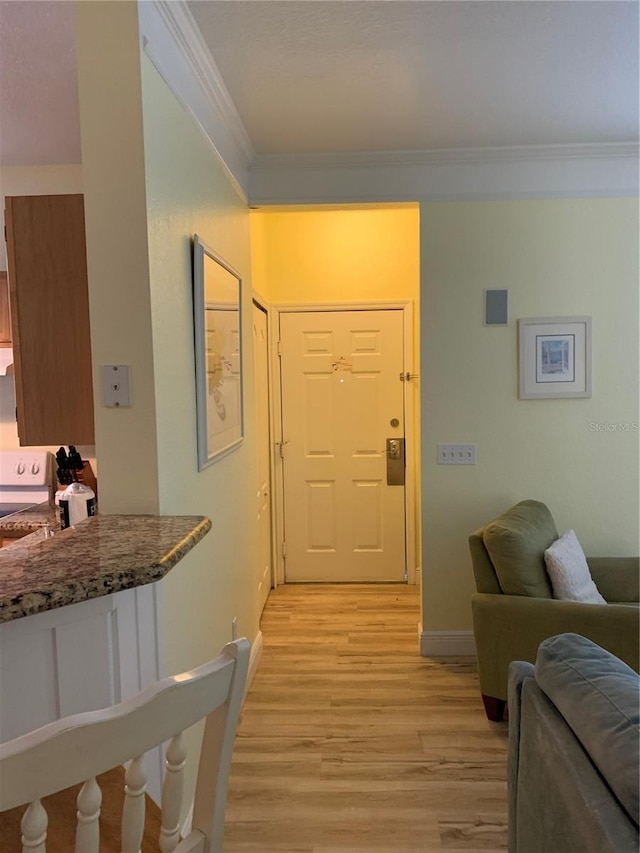 entryway with baseboards, light wood-type flooring, and crown molding
