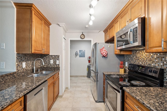 kitchen featuring dark stone counters, sink, light tile patterned floors, ornamental molding, and stainless steel appliances