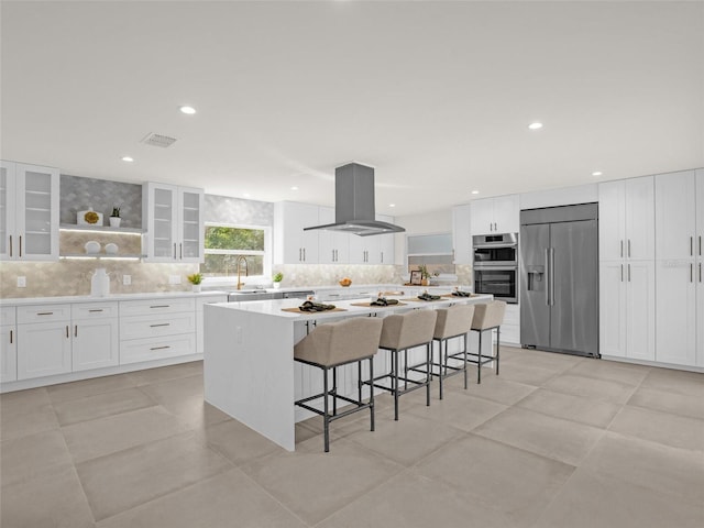 kitchen featuring a center island, white cabinets, a kitchen breakfast bar, appliances with stainless steel finishes, and island exhaust hood