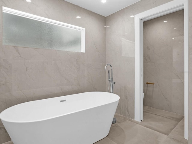 bathroom with a washtub and tile walls