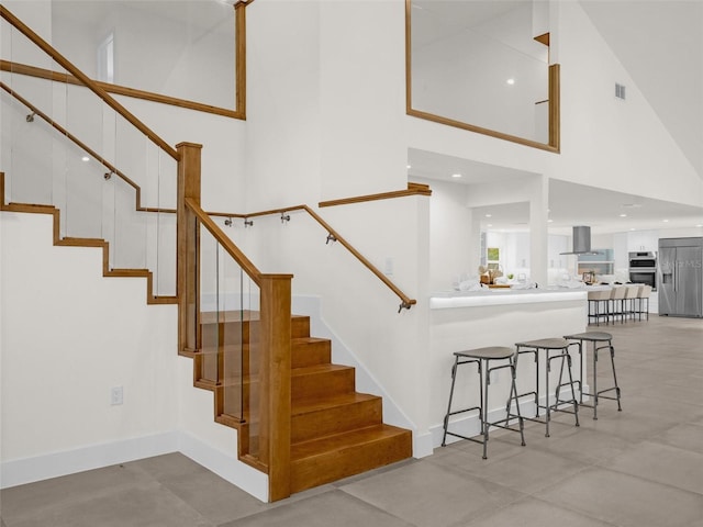 stairway featuring a towering ceiling and concrete floors