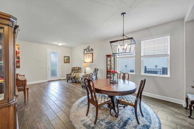 dining room featuring a chandelier, dark wood-style flooring, a wealth of natural light, and baseboards