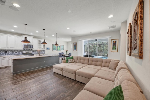 living room featuring recessed lighting, dark wood-style flooring, visible vents, and a textured ceiling