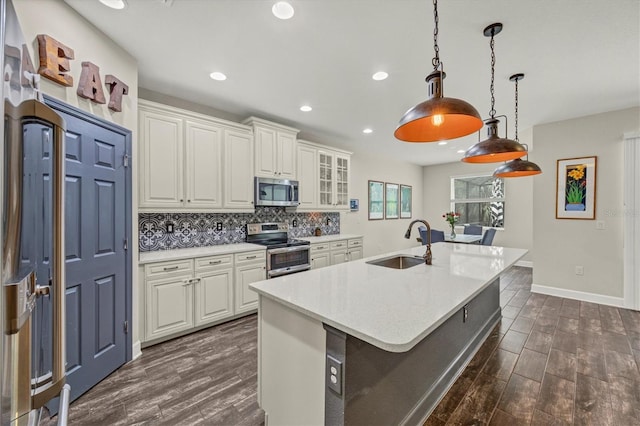 kitchen with white cabinets, decorative backsplash, appliances with stainless steel finishes, light countertops, and a sink