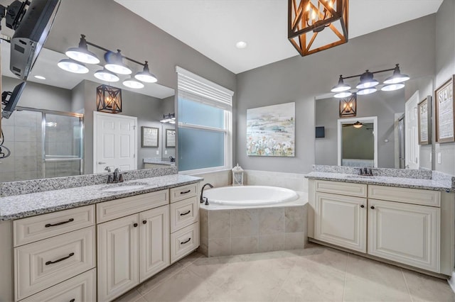 full bathroom featuring a stall shower, two vanities, a sink, and a bath