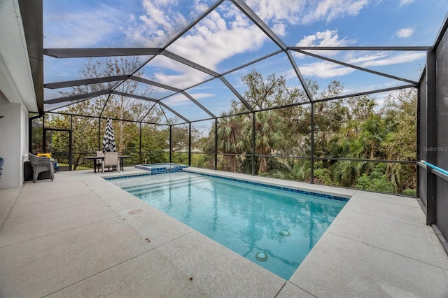 view of pool with a pool with connected hot tub, glass enclosure, and a patio