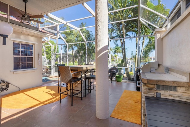 view of patio with glass enclosure, area for grilling, and a bar