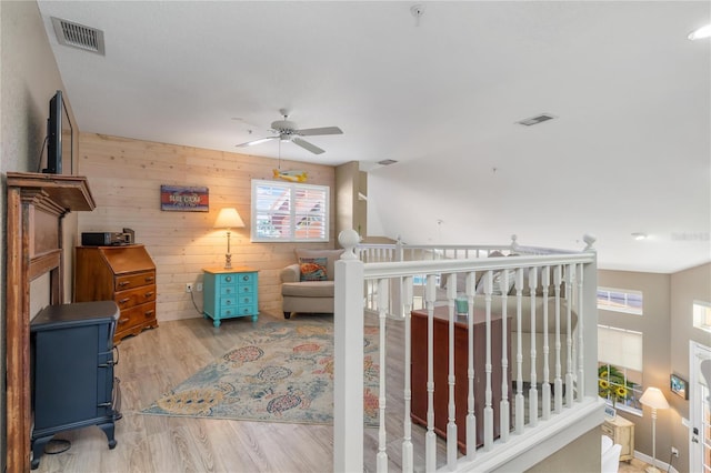 interior space with ceiling fan, wood walls, and light wood-type flooring