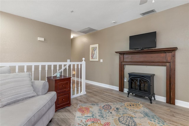 living room with light hardwood / wood-style floors and a wood stove