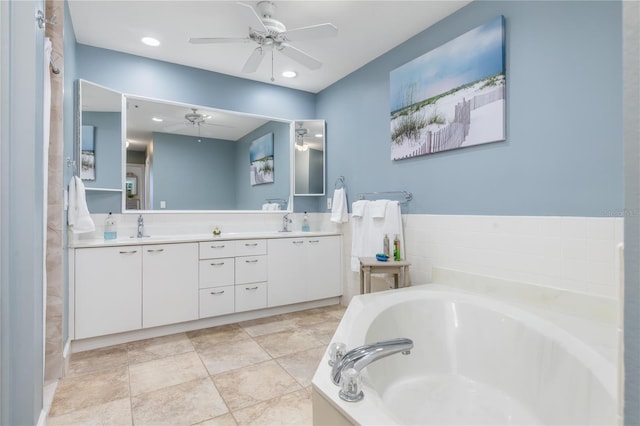 bathroom with tiled tub, ceiling fan, and vanity