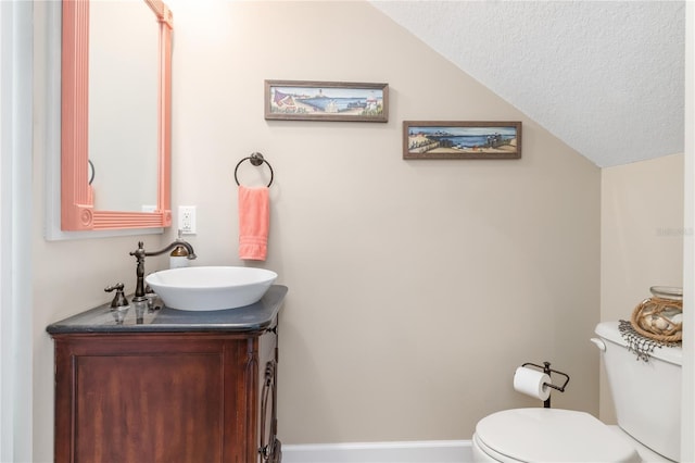 bathroom featuring vanity, toilet, a textured ceiling, and vaulted ceiling