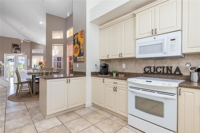 kitchen featuring kitchen peninsula, decorative backsplash, white appliances, ceiling fan, and dark stone countertops