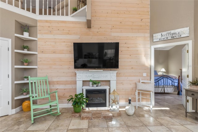 living room with wood walls, built in features, and a high ceiling