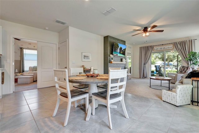 carpeted dining room featuring a fireplace, ceiling fan, and a healthy amount of sunlight