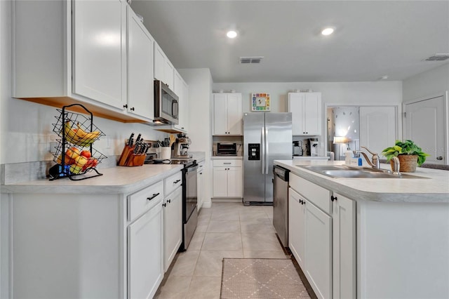 kitchen with white cabinetry, sink, a center island with sink, light tile patterned flooring, and appliances with stainless steel finishes